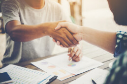 Nella foto due persone si stringono la mano in segno di accordo e mediazione